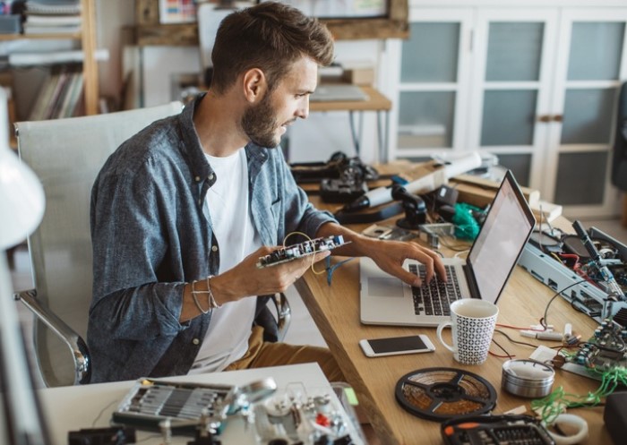 Uomo che lavora al laptop in una officina